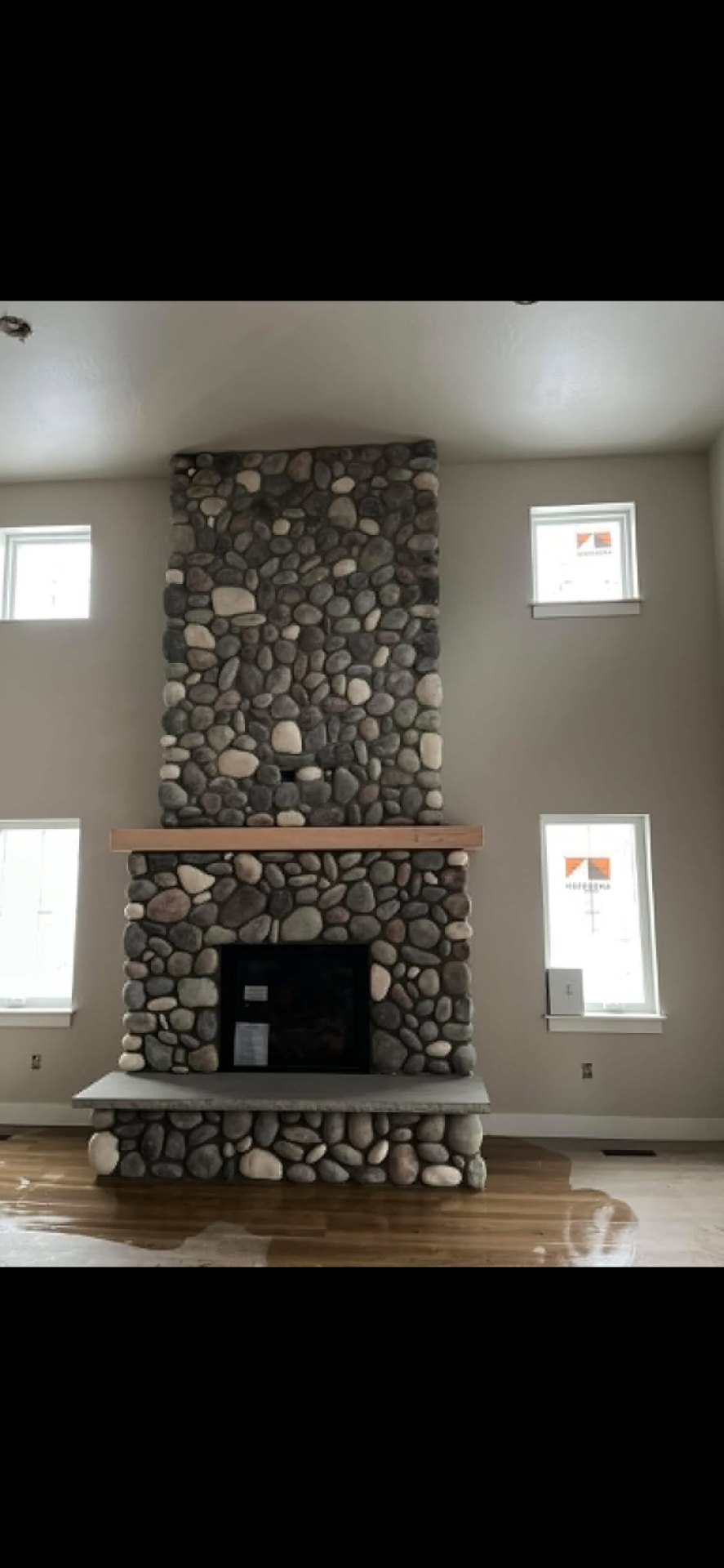 Two-story river rock fireplace with timber mantel
